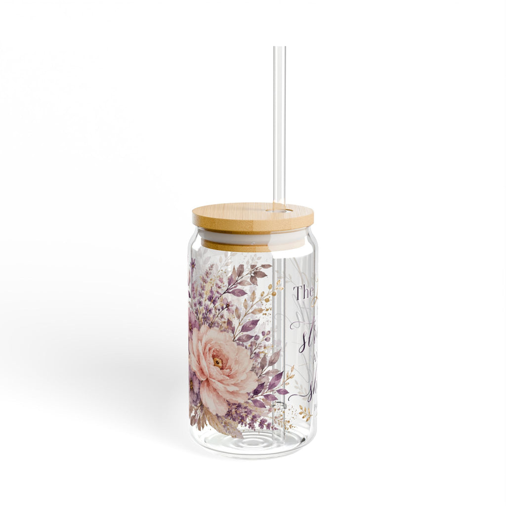 A clear glass tumbler with a light wood lid and a clear straw, decorated with a pink rose and purple floral pattern on the front, set against a plain white background.