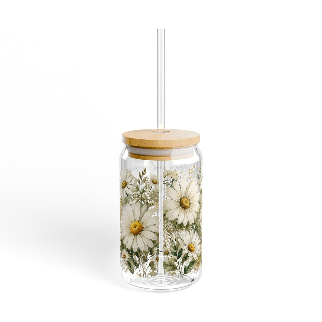 A clear glass tumbler with a bamboo lid and a clear straw, decorated with a vintage-style floral print of white daisies with yellow centers and green leaves, set against a plain white background.