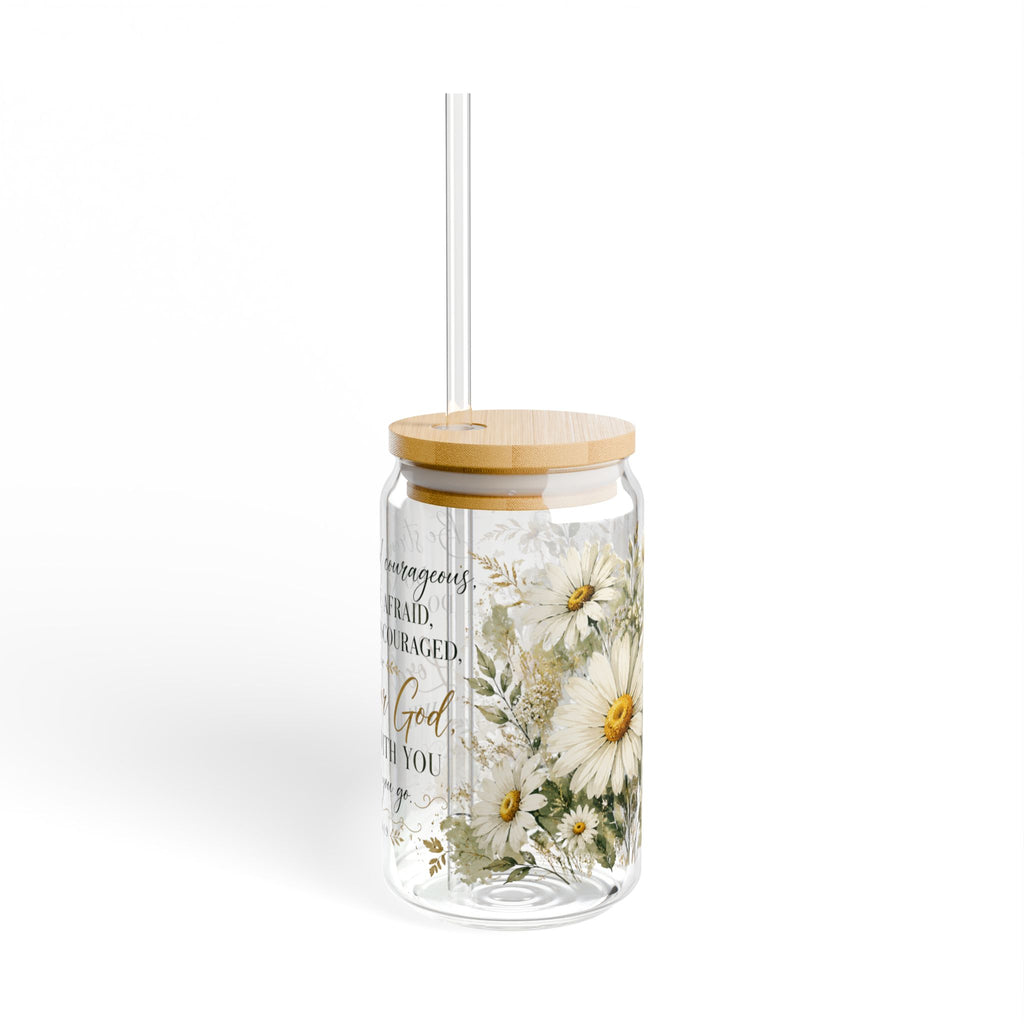 A clear glass tumbler with a light wood lid and clear straw, decorated with white daisy flowers and gold script text, shown on a white background.