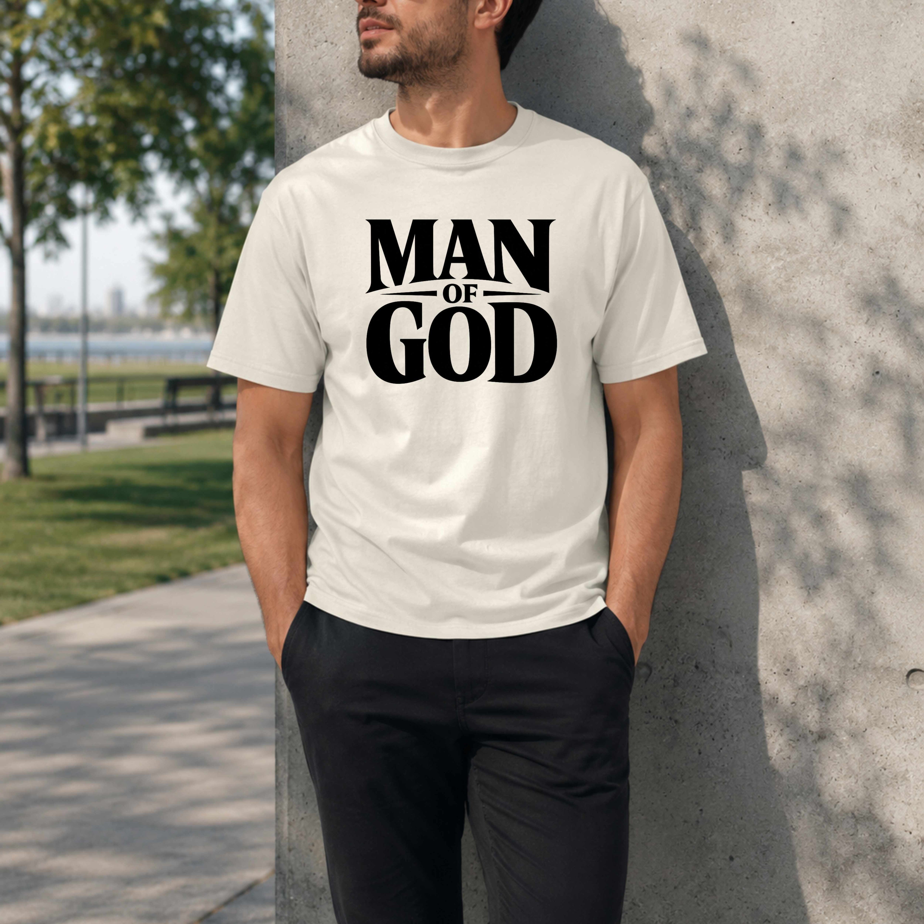 Person wearing a white t-shirt with 'Man of God' text, standing against a concrete wall outdoors.