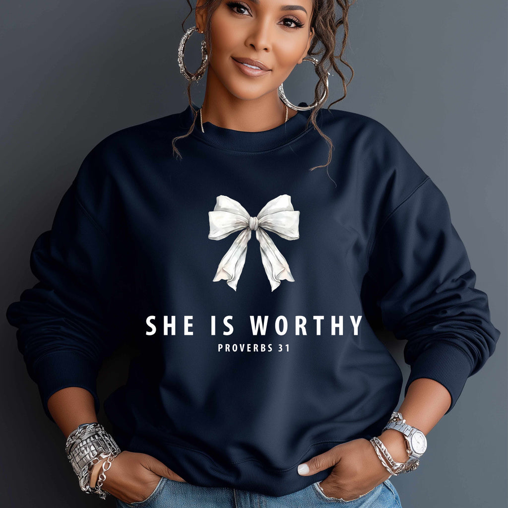 Woman wearing a navy sweatshirt with a white bow and 'SHE IS WORTHY Proverbs 31' text.